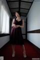 A woman in a purple dress standing in a hallway.