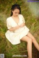 A woman in a white dress sitting in the grass.