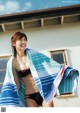 A woman in a bikini holding a blue and white towel.