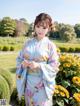 A woman in a blue kimono standing in a field of flowers.