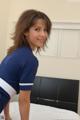 A woman in a blue and white uniform standing on a bed.