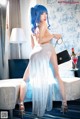 A woman with blue hair is posing on a bed.