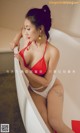 A woman in a red bikini sitting in a bathtub.