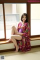 A woman in a kimono sitting on a window sill.