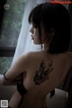 A woman with a tattoo on her back sitting on a couch.