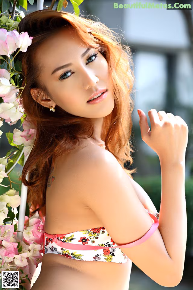 A woman in a bikini posing in front of flowers.