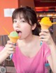 A young woman eating two ice cream cones in a restaurant.