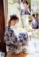 A woman in a blue and white kimono sitting on a window sill.