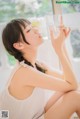 A woman sitting on a window sill drinking water.