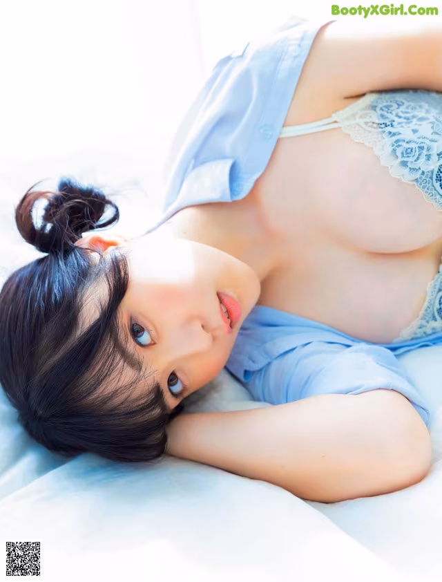 A woman laying on top of a bed in a blue shirt.
