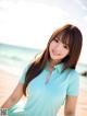 A woman in a blue shirt standing on a beach.