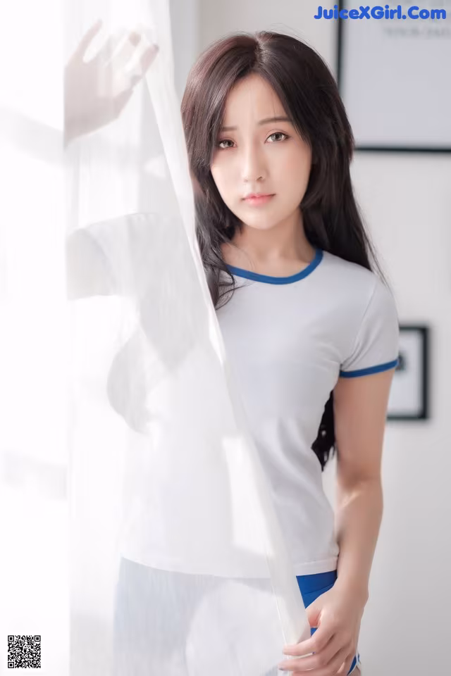 A woman in a white shirt and blue shorts posing for a picture.