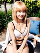 A woman in a white bikini sitting on a wooden bench.