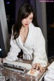 A woman in a white robe sitting at a table.