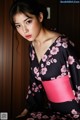 A woman in a black and pink kimono posing for a picture.