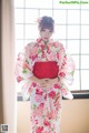 A woman in a kimono standing in front of a window.