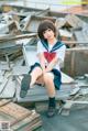 A woman in a school uniform sitting on a pile of rubble.