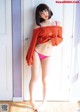 A woman in a red sweater and pink panties posing for a picture.