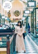 A woman in a long dress standing in a shopping mall.