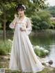 A woman in a white dress standing by a lake.