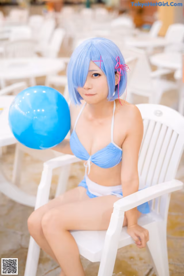 A woman in a blue bikini sitting on a white chair.