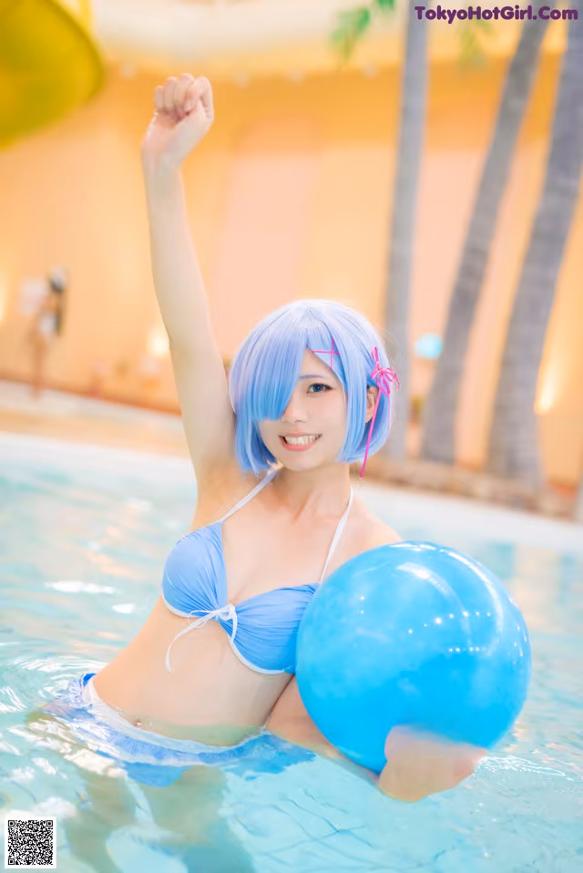 A woman in a blue bikini holding a blue ball in a pool.